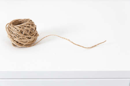 A skein of craft twine on a white chest of drawers.