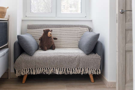 Gray soft sofa with 2 pillows. Modern design sofa in 70th style near window in an empty empty room. copyspace.の写真素材