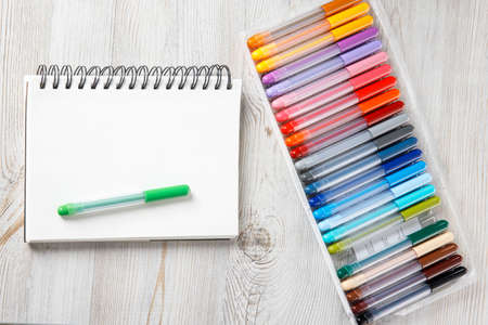 view from above. Twenty-four colored markers and a notebook are on the drawing table.
