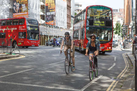 London, UK - 20 September 2021, A woman and man rides a bicycles on the road among carsのeditorial素材