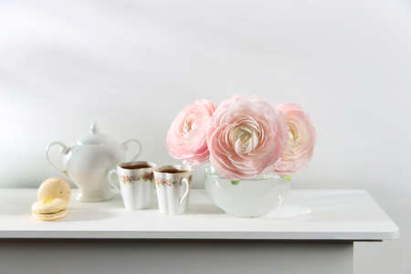 Three pale pink ranunculus in a transparent round vase on the white windowsill. copyspace. Place for textの写真素材