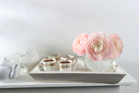 Three pale pink ranunculus in a transparent round vase on the white windowsill. copyspace. Place for textの写真素材