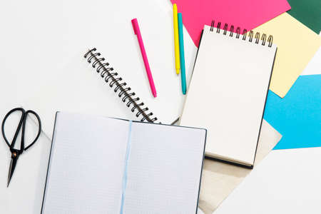 A lot of notebooks on springs, multi-colored paper: blue, red, green, gold, pens and scissors. office concept. Place for textの写真素材