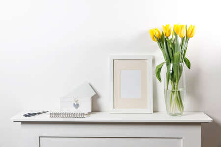 Bouquet of yellow tulip in the glass vase on white table