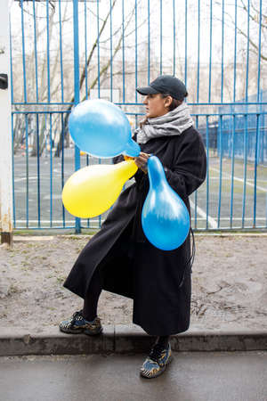 Moscow, Russia - 12 April 2022, People came to the court to support the arrested students in the case Doxa. A woman inflates yellow and blue balloons in support of Ukraineのeditorial素材