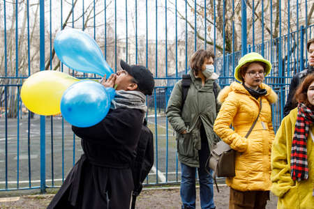 Moscow, Russia - 12 April 2022, People came to the court to support the arrested students in the case Doxa. A woman inflates yellow and blue balloons in support of Ukraineのeditorial素材