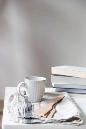 Two white mugs, a kitchen towel, a napkin and wooden frying utensils on the table. Defocus.の写真素材