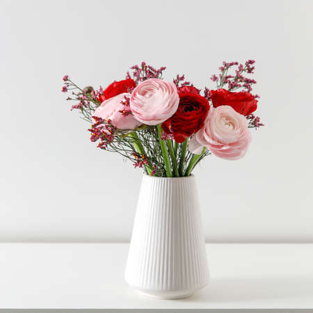 Persian pink buttercup in a beige wicker basket on a white background. copy space