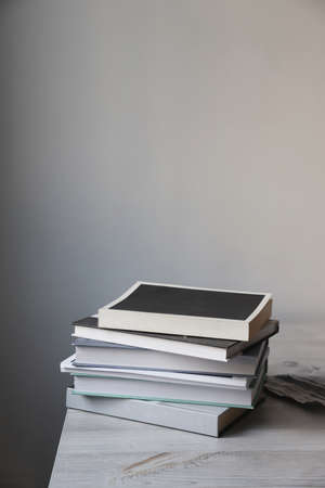 There is a stack of books on a beige table against a white wall. Scandinavian style. minimalism....