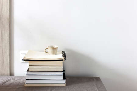 There is a stack of books on a beige table against a white wall. Scandinavian style. minimalism. Place for textの写真素材