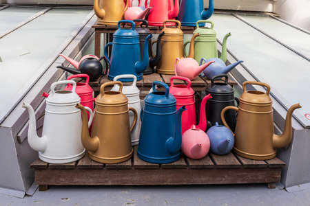 Different sizes of different colors of watering cans for sale in a flower shopの写真素材