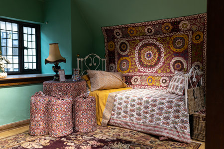 LONDON - NOVEMBER 30, 2022: Liberty's, Luxury department store. Interior with a bed, a red patchwork bedspread, pillows and a carpet on a green wall.のeditorial素材