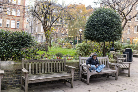 LONDON, ENGLAND - December 18 , 2022, The yard of St Paul's Church, affectionately known as The Actors' Church. Girl reading a book sitting on a wooden benchのeditorial素材