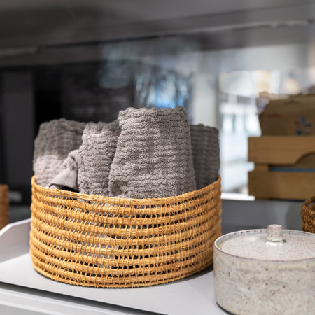 Rattan wicker basket with gray terry face towels in the bathroomの写真素材