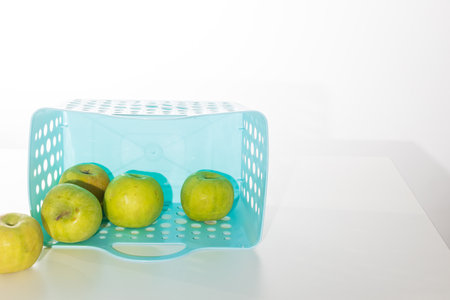 Green apples of the Antonovka variety fall out of a blue plastic container bag