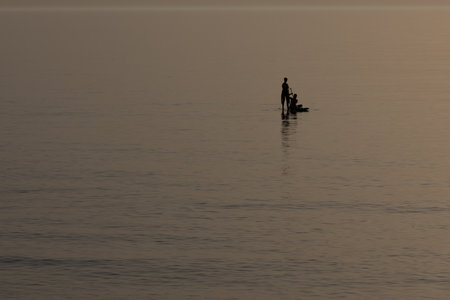 Haifa, Israel 12 March 2023, Group of young people doing SUP. Stand up paddle board couple paddleboarding .Selective focus. People blured with water spray. Sunset. Back light. Mediterranean.の写真素材