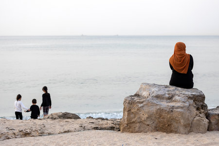 Haifa, Israel 12 March 2023, A woman in traditional Muslim clothing sits on a stone, looks at the...