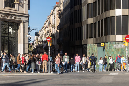 Barcelona, Spain - March 13, 2023: People are waiting for the green traffic light to cross the road...