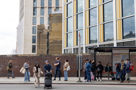 LONDON, ENGLAND - April 12, 2023 People are waiting for the bus at the bus stop. Representatives of...