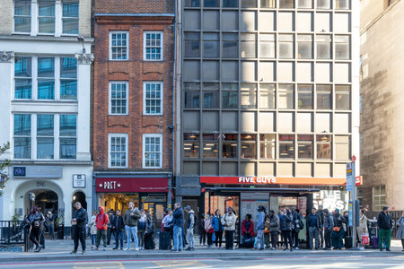 LONDON, ENGLAND - April 12, 2023 People are waiting for the bus at the bus stop. Representatives of...