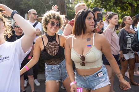 Haifa, Israel - June 24, 2023: People with protest signs in preparation to the annual LGBTQ pride parade. Girl in a mesh top dancingのeditorial素材