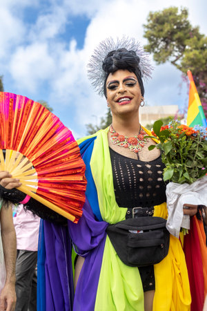 Haifa, Israel - June 24, 2023: People with protest signs in preparation to the annual LGBTQ pride parade. Drag queen holding a rainbow fanのeditorial素材