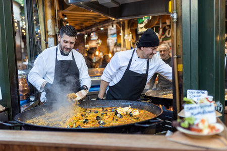 LONDON, UK - December 10, 2023 Male sellers prepare paella in Borough Marketのeditorial素材