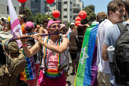 Haifa, Israel June 21, 2024, Pride Parade. A man plays the flute in the crowd next to drummers.のeditorial素材