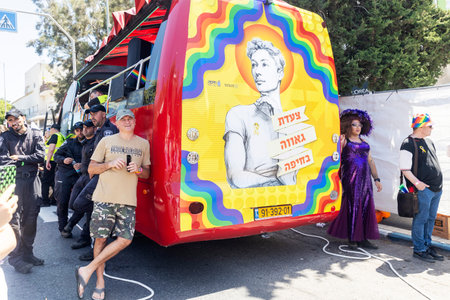 Haifa, Israel June 21, 2024, Pride Parade. Soldiers and members of the public hide in the shadow of a bus advertising the Pride parade, waiting for the parade to begin.のeditorial素材