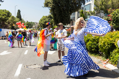 Haifa, Israel June 21, 2024, Pride Parade. Drag queen Lalika, wearing a dress made from the Israeli flag, twirls and dances in the crowd.のeditorial素材