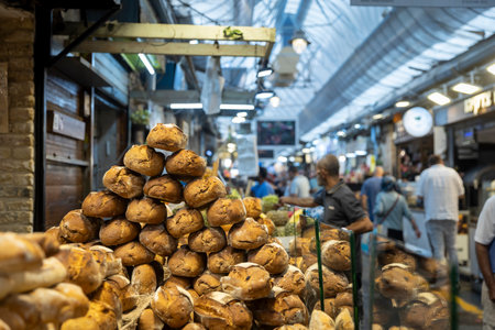 Jerusalem, Israel - October 1, 2024. A man seller sells fresh bread to visitors at the Mahane Yehuda market. Near Shabbatの写真素材