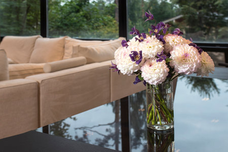 A bouquet of white chrysanthemums and blue bells on a black polished table in the living roomの写真素材