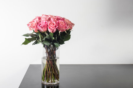 A bouquet of red roses in a vase on the table. Space for text.の写真素材