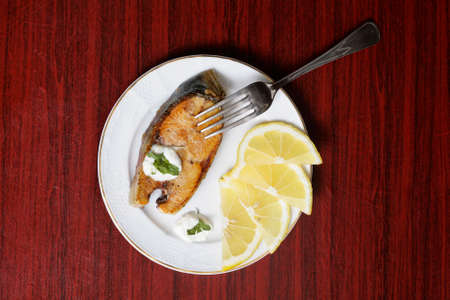 Baked fish piece served over white plate on tableの写真素材
