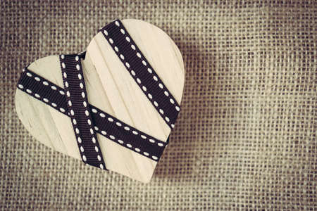 Wooden heart blank with decorated ribbon on sack material background