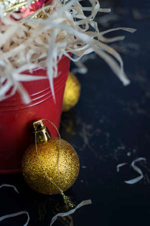 Gold Christmas balls resting against a red bucket.の写真素材