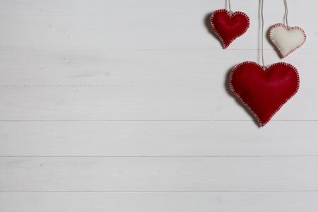 Wooden background with red and white cloth hearts.の写真素材