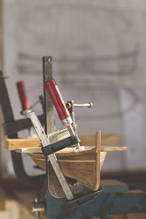 old man working on creating a wooden model of a boatの写真素材