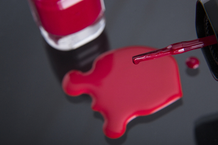 close up of the brush of a nail polish with poured nail polish and glass flaskの写真素材