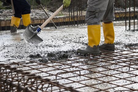 two bricklayers at work on a construction site during the laying of concrete to build the...