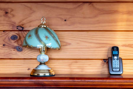 Bedroom lamp and Uniden phone on bed post against a timber wallの写真素材