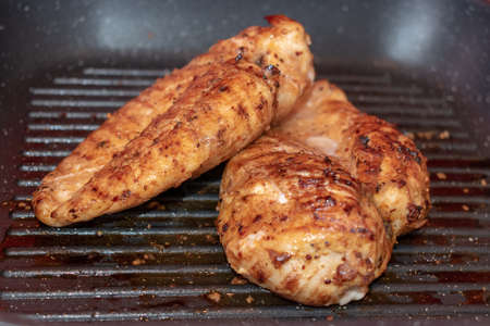 Two golden crispy marinated grilled chicken breasts on a panの写真素材