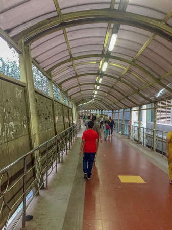 Mumbai India, Saturday Jan 13th 2018 - Pedestrians walk along an illuminated sheltered footbridge during the dayのeditorial素材