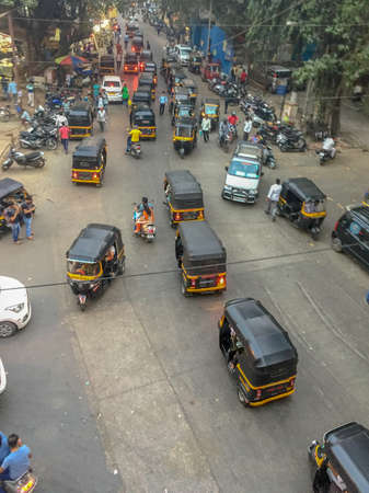 Mumbai India, Saturday Jan 13th 2018 - Black and yellow auto-rickshaws clog up a busy intersection driving any which way during the dayのeditorial素材