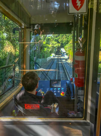 Wellington,New Zealand, 2nd April 2018 - the driver of a Wellington Cable Car looks through his windshield down the rail track as he calmly reads a bookのeditorial素材