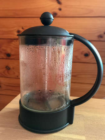 Empty coffee plunger on a table against a timber wall backgroundの写真素材