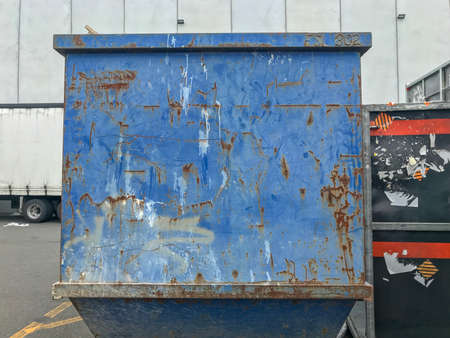 Side view of a rusting blue metal container standing at the parking yard during the daytimeの写真素材