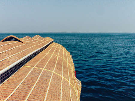Top view of the thatched roof of a houseboat as it floats gently down the backwaters in...