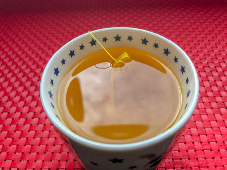 Point of view of a mug of turmeric tea on a red matの写真素材