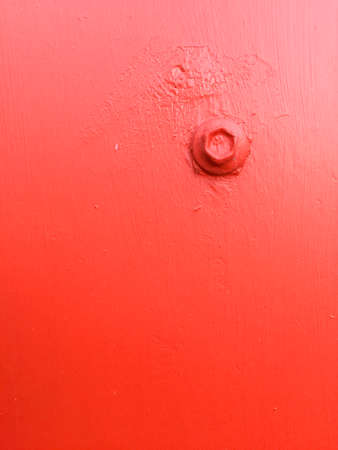 Red painted bolt on a red surface creating a minimalist abstractionの写真素材